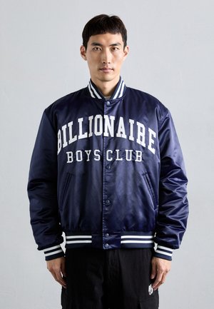 Navy satin bomber jacket with "Billionaire Boys Club" in white lettering. Features striped ribbed cuffs and waistband, snap buttons, and side pockets.