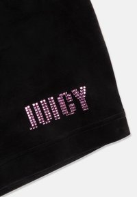 Crni sametni šortsi s otisnutim natpisom "JUICY" u ružičastim rhinestones na donjem lijevom dijelu nogavice. Glatka tekstura i uredni rubovi.