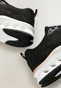 Sneaker nere con una tomaia in mesh testurizzato, suola intermedia bianca con ammortizzazione ad aria e suola in gomma nera con battistrada pattern. Publishers