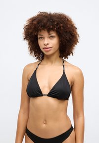 Μαύρο μπικίνι τοπ σε τρίγωνο σχήμα, φτιαγμένο από απαλό ύφασμα, με λεπτές τιράντες που διαθέτουν λεπτομέρειες με το λογότυπο και με ραμμένο κεντρικό μέρος για καλύτερη εφαρμογή.