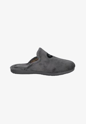 Zapatilla de casa gris y peluda con puntera redondeada, diseño slip-on y superficie texturizada. Presenta un acento de logo negro en el lateral y una suela plana.