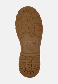 Brown rubber shoe sole with textured grip pattern; features "CAMper" and "BRIDGE XTRAGRIP" embossed in central area; size 42 indicated.