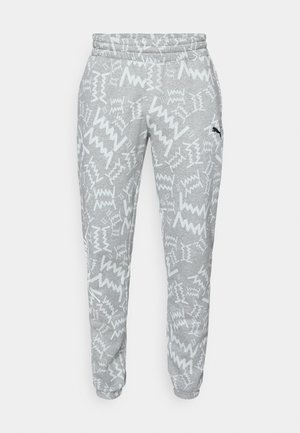 Pantalon de survêtement gris avec des motifs en zigzag blancs, taille élastique, chevilles cintrées et petit logo Puma noir sur la cuisse droite.