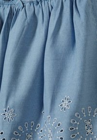 Gonna in cotone azzurro chiaro con vita arricciata e ricamo floreale bianco all'orlo, che mette in mostra un tessuto texturizzato e dettagli di cucitura intricati.