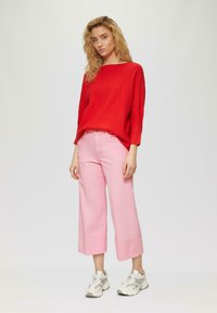 Pull rayé rouge, jean large rose et baskets grises. La tenue présente une coupe décontractée avec un col scoop et une longueur de pantalon raccourcie.