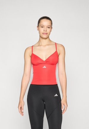 Red athletic tank top with a V-neck and thin straps, featuring white side accents and a small logo on the front. Black leggings with logo.