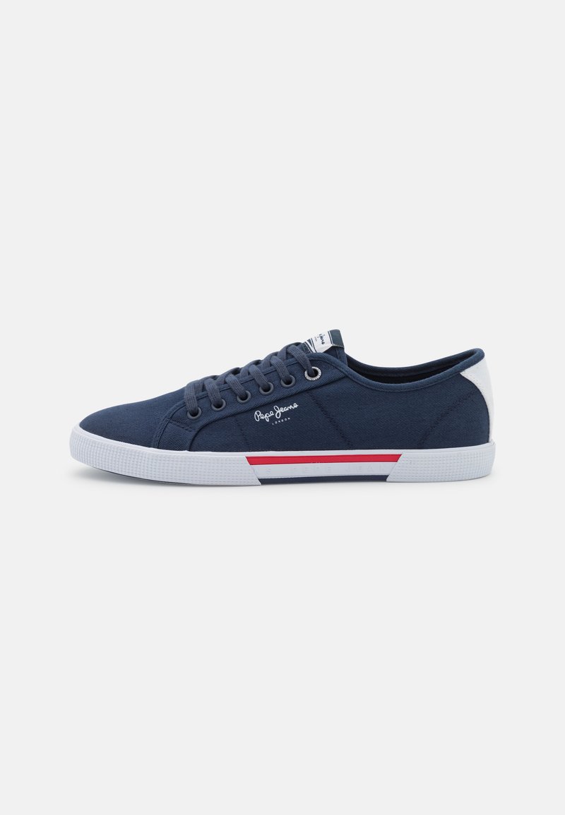 Granatowe płócienne sneakersy z białą gumową podeszwą, z czerwono-białym akcentem, sznurowanym designem i logo z boku.