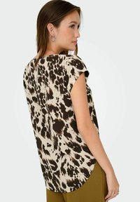 Top a maniche corte con stampa animale marrone e crema, caratterizzato da un orlo arrotondato e una chiusura con zip sul retro. Tessuto morbido con una vestibilità comoda.