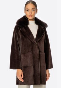 Abrigo de piel sintética marrón con un gran cuello, mangas largas y bolsillos frontales tipo parche. Textura suave con un corte relajado.
