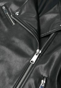 Veste en cuir noir avec fermetures éclair et détails à boutons-pression ; texture lisse, avec quincaillerie argentée et poches inclinées pour le design.