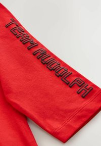 Red cotton t-shirt with black embroidered text "TEAM RUDOLPH" along the sleeve. Short sleeve design with smooth texture.