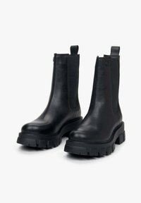 Czarne botki za kostkę wykonane z gładkiej skóry, z elastycznymi bocznymi panelami, zaokrąglonymi czubkami i grubymi gumowymi podeszwami zapewniającymi lepszą przyczepność i stabilność.