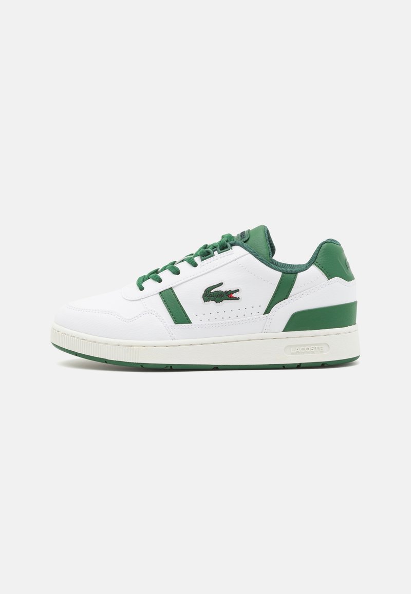 Baskets blanches avec accents verts, en cuir, avec des détails perforés et une semelle en caoutchouc. Logo Lacoste affiché de manière proéminente sur le côté.