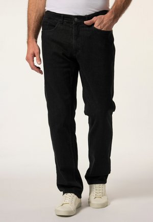 Vaqueros de denim negro con un corte recto, diseño de cinco bolsillos y una textura sutil. Llevados con zapatillas blancas y una camisa blanca ajustada.