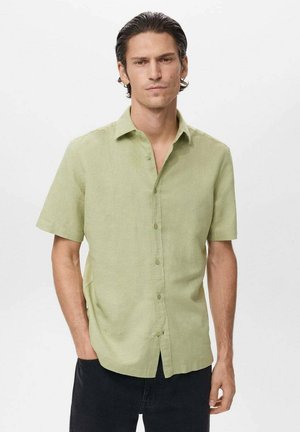 Camisa de manga corta verde claro hecha de una tela suave, con botones en el frente, cuello clásico y un corte relajado, combinada con pantalones oscuros.