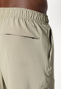 Light green athletic shorts with an elastic waistband, side pocket with zip closure, and subtle vertical stripes. "Dri-Fit" logo visible.