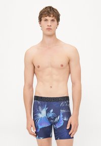 Boxerii pentru bărbați în nuanță de navy cu un model floral în nuanțe de albastru și mov. Talie elastică marcată "UNDER" în negru. Textură de material neted.