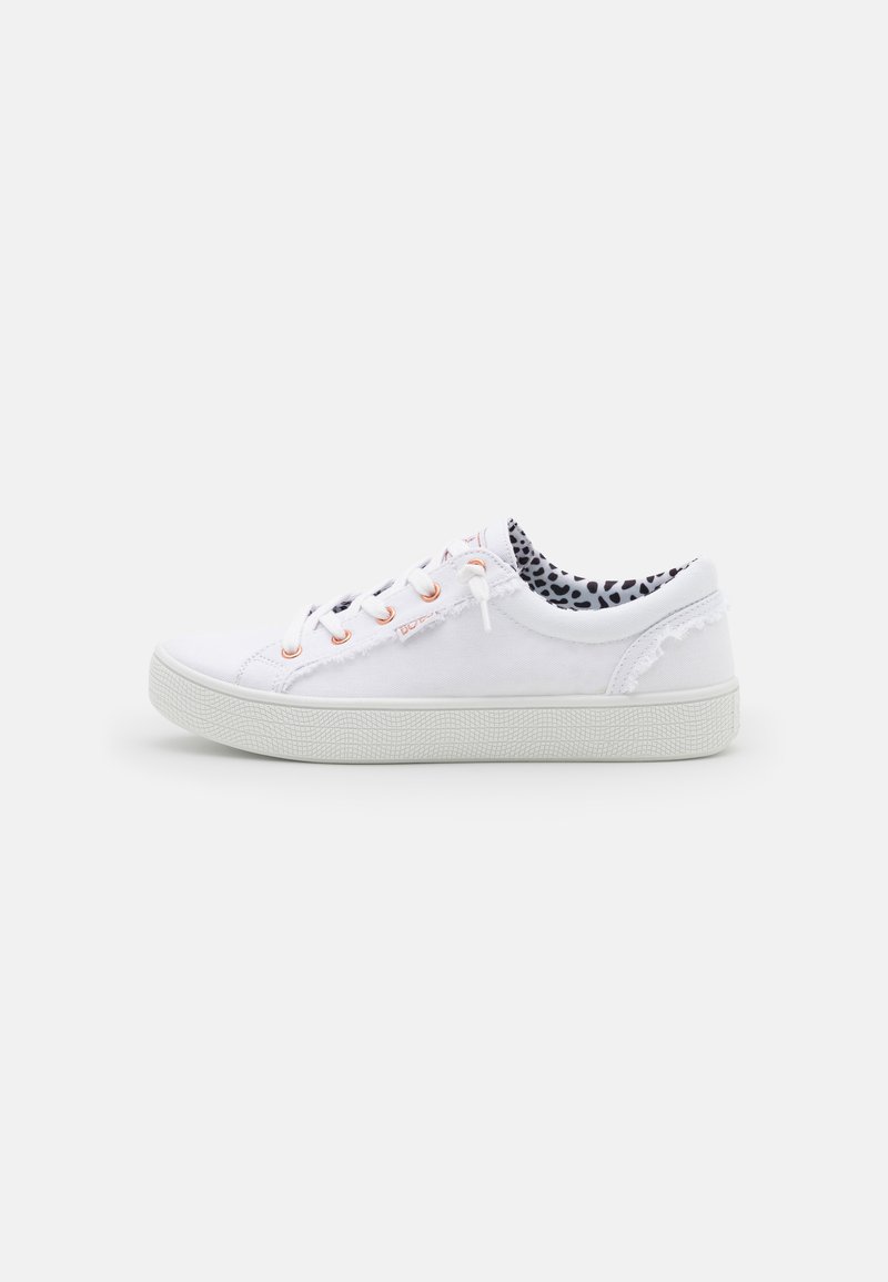 Sneakers bianchi in tela con punta tonda, suola testurizzata e occhielli arancioni. L'interno presenta un motivo a macchie bianche e nere.