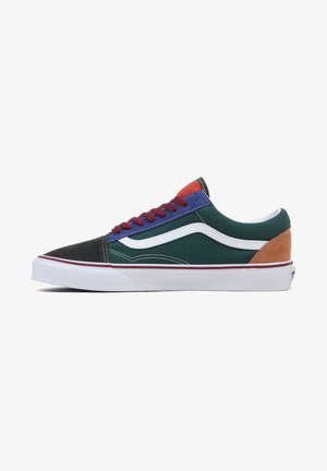 Zapato de skate bajo con puntera negra, paneles laterales verdes, ojales azules, cordones rojos, talón naranja, franjas onduladas blancas y suela blanca.