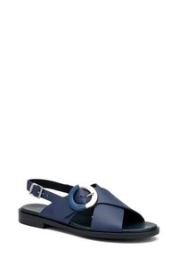 Sandalo blu navy con design a cinturino incrociato, in pelle liscia, punta aperta, chiusura con fibbia e dettaglio hardware circolare.