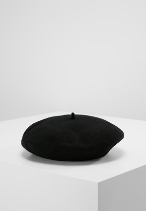 Béret en laine noire avec une forme ronde et plate et un design à touffe centrale. Texture douce, surface lisse et sans motifs ni accessoires visibles.