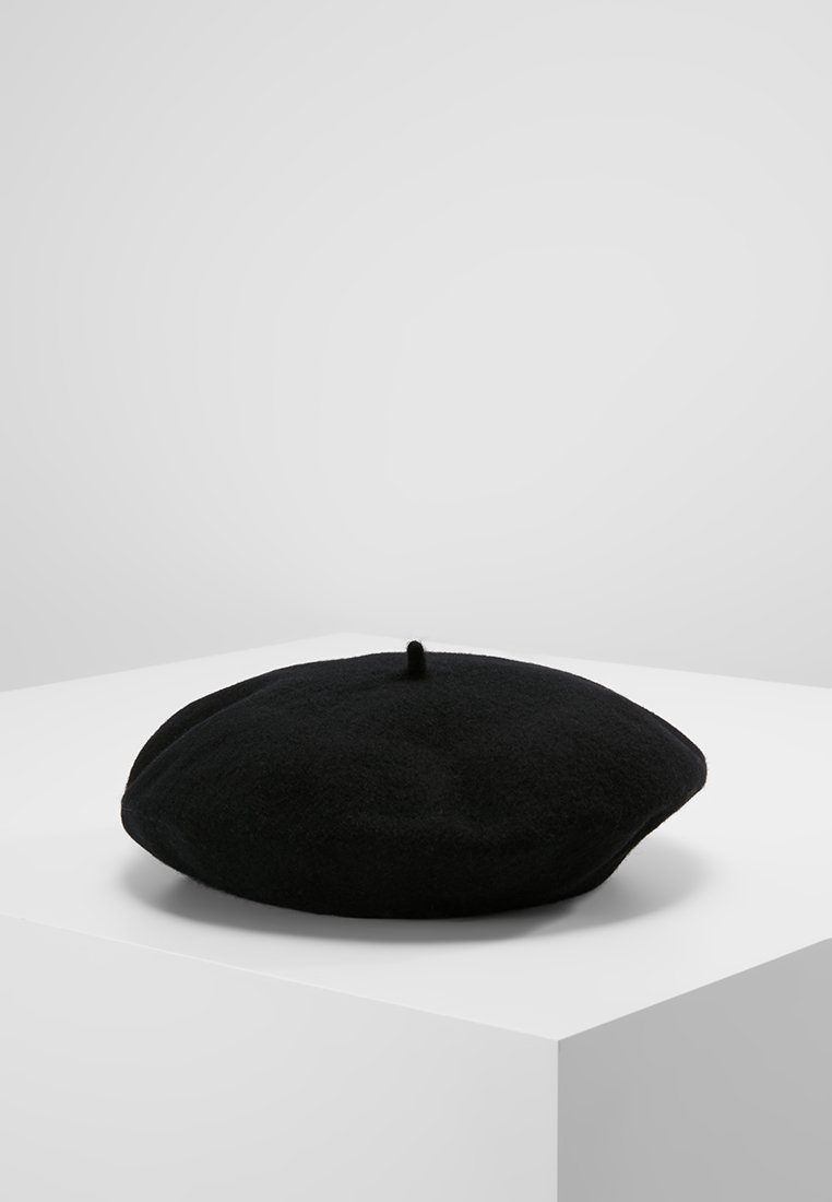 Beret de lã preto com forma redonda e plana e um design central de tufos. Textura suave, superfície lisa e sem padrões ou acessórios visíveis.