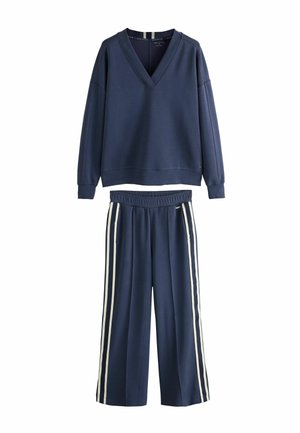 Marineblauwe trui met lange mouwen en V-hals, elastische tailleband, marineblauwe broek met witte zijstrepen.