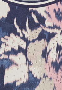 Strickstoff mit einem blauen, rosa und cremefarbenen abstrakten Muster, verziert mit kleinen metallischen Akzenten. Rippkragen in Marineblau.