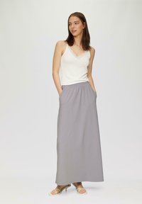 Weißes, geripptes Top mit Spitzenbesatz, kombiniert mit einem grauen Maxirock mit elastischem Bund und Seitentaschen. Elegantes und einfaches Design.