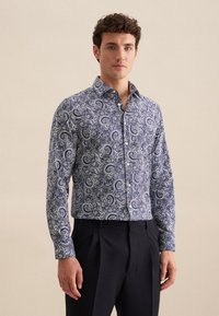 Koszula zapinana na guziki w niebiesko-białym wzorze paisley, wykonana z lekkiego materiału; ma stożkowy kołnierz i długie rękawy.