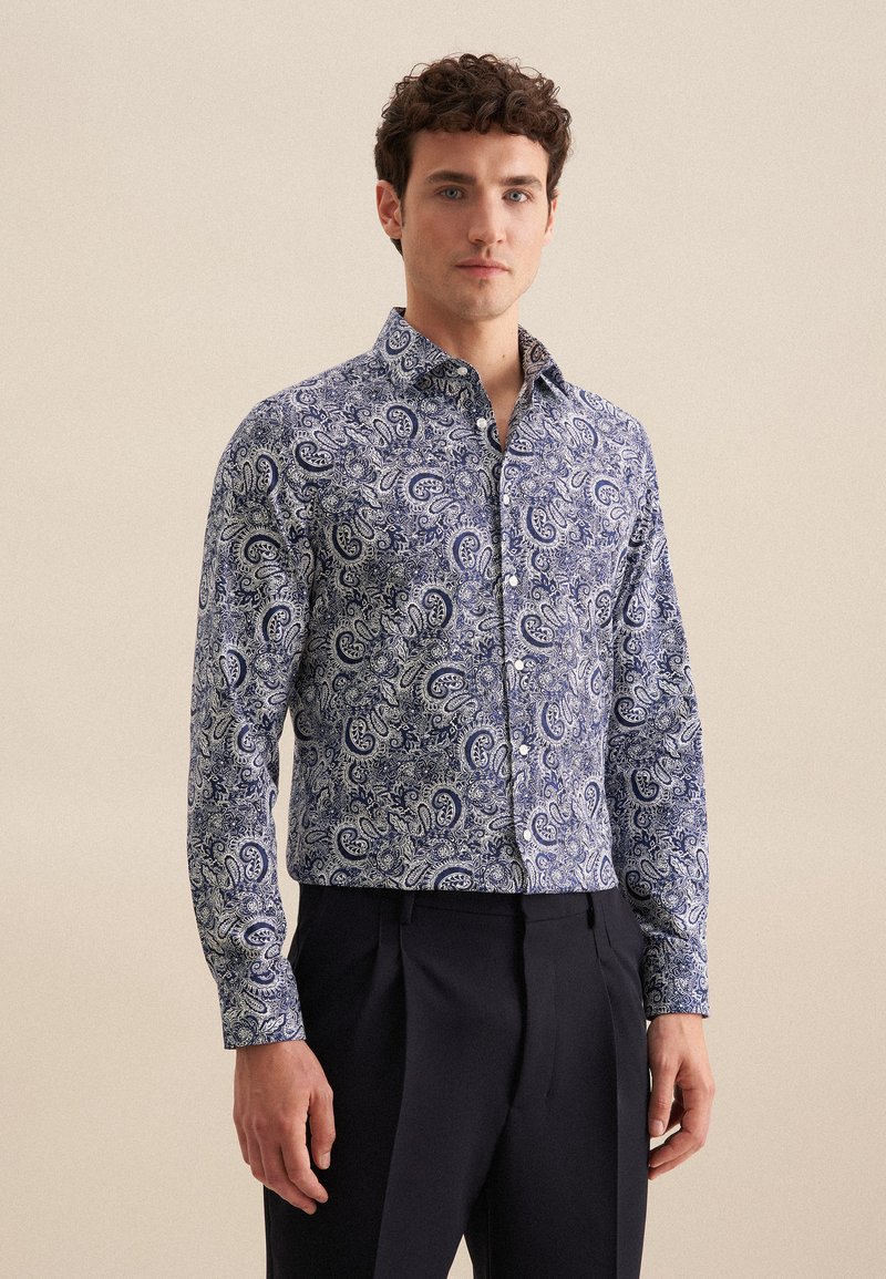 Koszula zapinana na guziki w niebiesko-białym wzorze paisley, wykonana z lekkiego materiału; ma stożkowy kołnierz i długie rękawy.