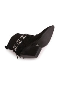Bota de tobillo de ante sintético negro con intrincados acentos plateados, puntera afilada, tacón texturizado y detalles de cordones. Suela plana y texturizada.