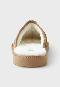 Kohvath all muudatustega ja pehme valge karvase voodriga, avatud seljaga disain ja tekstureeritud välistald. Materjal tundub kestva ja mugavana siseruumides kasutamiseks.