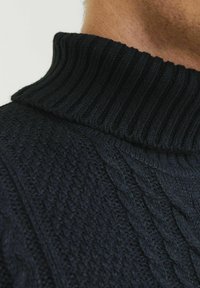 Pull à col roulé côtelé bleu marine avec des motifs de tricot en relief, en mélange de laine douce, et un col ajusté.