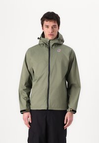 Ελαφρύ πράσινο αδιάβροχο μπουφάν με φερμουάρ, ρυθμιζόμενη κουκούλα και λογότυπο. Διαθέτει μαύρες λεπτομέρειες και ελαστικούς καρπούς.