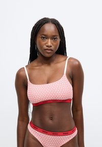 Ružová braletka a bikini set s motívom srdiečok, tenkými ramienkami a červeným pruhom s logom "HUGO". Hladká látka s elastickým strihom.