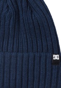Gorro de punto en color navy con textura acanalada. Presenta una etiqueta negra con un logo blanco en la parte inferior, diseñado para proporcionar calor y comodidad.