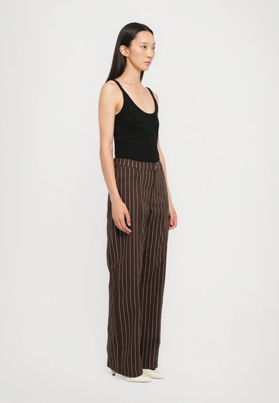 Black sleeveless top paired with brown pinstriped wide-leg trousers. The trousers feature a high waist and a smooth fabric texture.