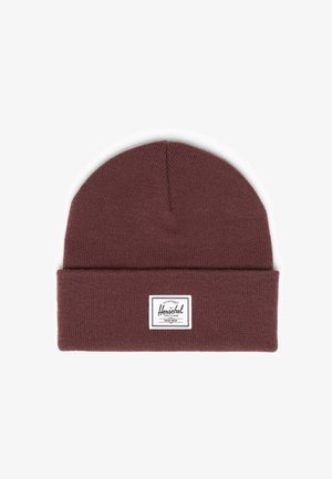 Bordeaux gebreide beanie met een opgerolde manchette. Heeft een wit rechthoekig label met zwarte tekst dat op de voorkant is genaaid. Zachte textuur en een consistent patroon.