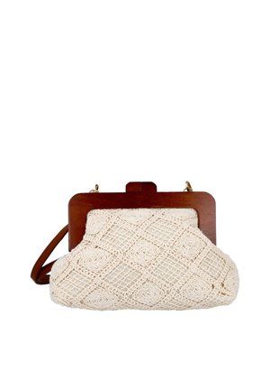 Pequeño bolso beige de ganchillo con patrones geométricos, marco de madera y una correa de cuero marrón sobre un fondo blanco.