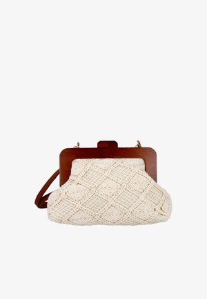 Pequeño bolso beige de ganchillo con patrones geométricos, marco de madera y una correa de cuero marrón sobre un fondo blanco.