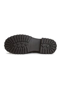 Suola di scarpa in gomma nera con profonde scanalature e motivi testurizzati. Presenta protuberanze circolari per la trazione e una sezione centrale liscia per il supporto.