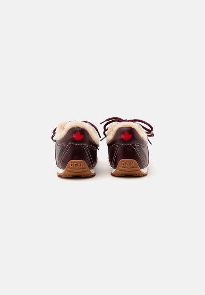 Paire de chaussures en cuir brun foncé avec doublure en fourrure, feuille d'érable rouge sur le talon, et texte "DEAN" et "DAN" sur les semelles, vue de dos.