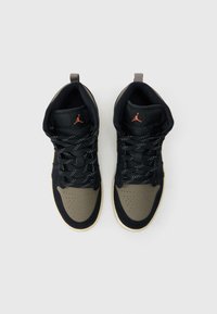 Μαύρα και ελιάς πράσινα ψηλά αθλητικά παπούτσια με διάτρητο κάλυμμα στα δάχτυλα, μαύρα κορδόνια και αντιθετικό πορτοκαλί λογότυπο. Υφασμάτινη υφή και λαστιχένια σόλα.