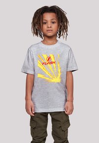 Camiseta de algodón gris con un logo rojo de "FLASH" y gráficos de relámpagos amarillos. Combinada con pantalones cargo color oliva.