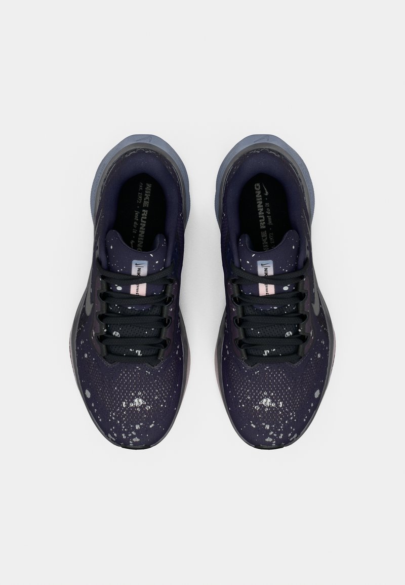 Par de zapatillas de correr Nike en negro y gris con un patrón moteado en blanco, vistas desde arriba sobre un fondo blanco.