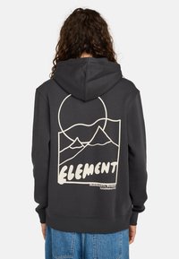 Sudadera con capucha gris oscuro y un bolsillo tipo canguro en la parte frontal. Presenta un gran gráfico en la parte posterior: montañas y un círculo en color crema claro.