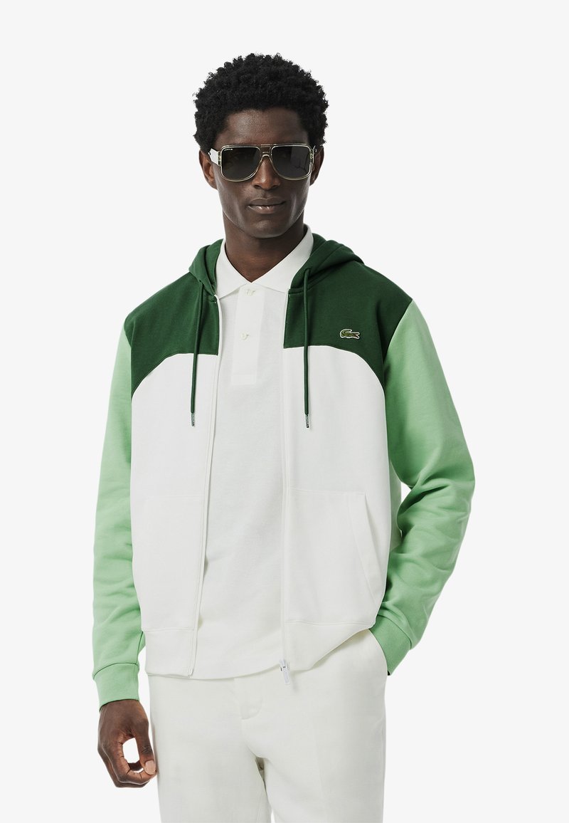 Groene en witte kleurblokken hoodie, met een ritssluiting, kangoeroezakken en een logo op de borst. Lichtgewicht stof.