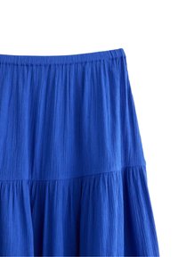 Gonna blu, con texture, dotata di una vita arricciata e design fluido. Presenta una silhouette a strati e un tessuto morbido e resistente alle pieghe.