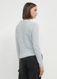 Helles, graues, weiches Strickpullover mit Rundhalsausschnitt, geripptem Saum und Ärmeln sowie einem leicht verkürzten Schnitt. Das Modell ist von hinten zu sehen, wobei die Rückendetails zur Geltung kommen.